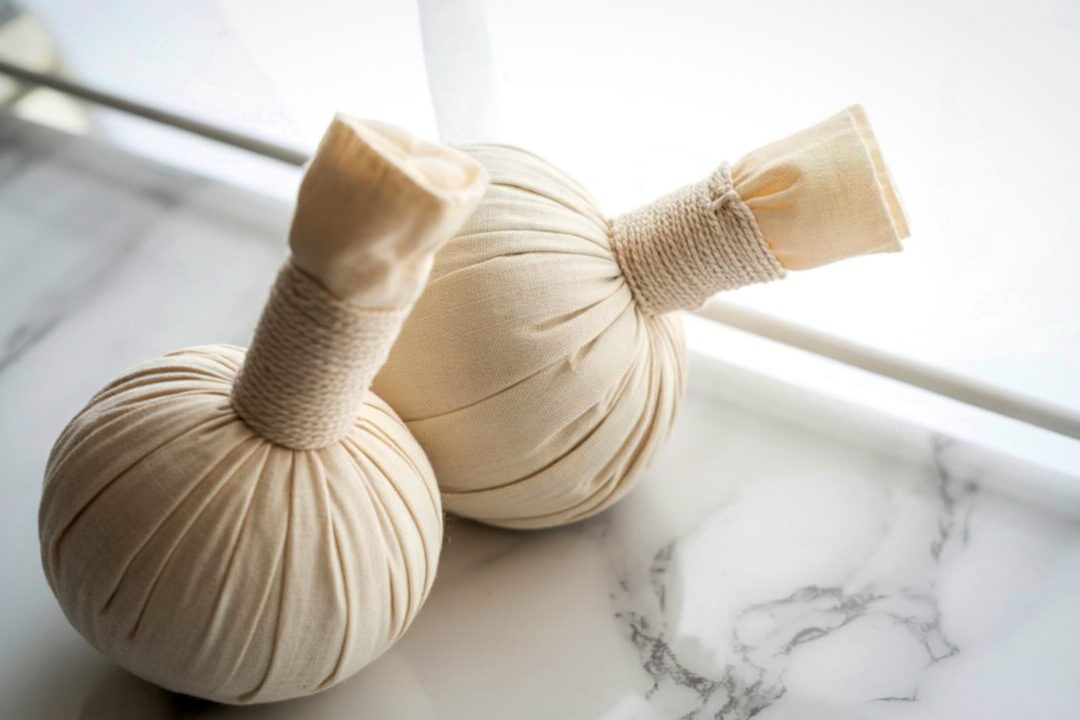 温かいハーブボール（キリ）を押し当てて発汗を促すピンダ・スウェダ